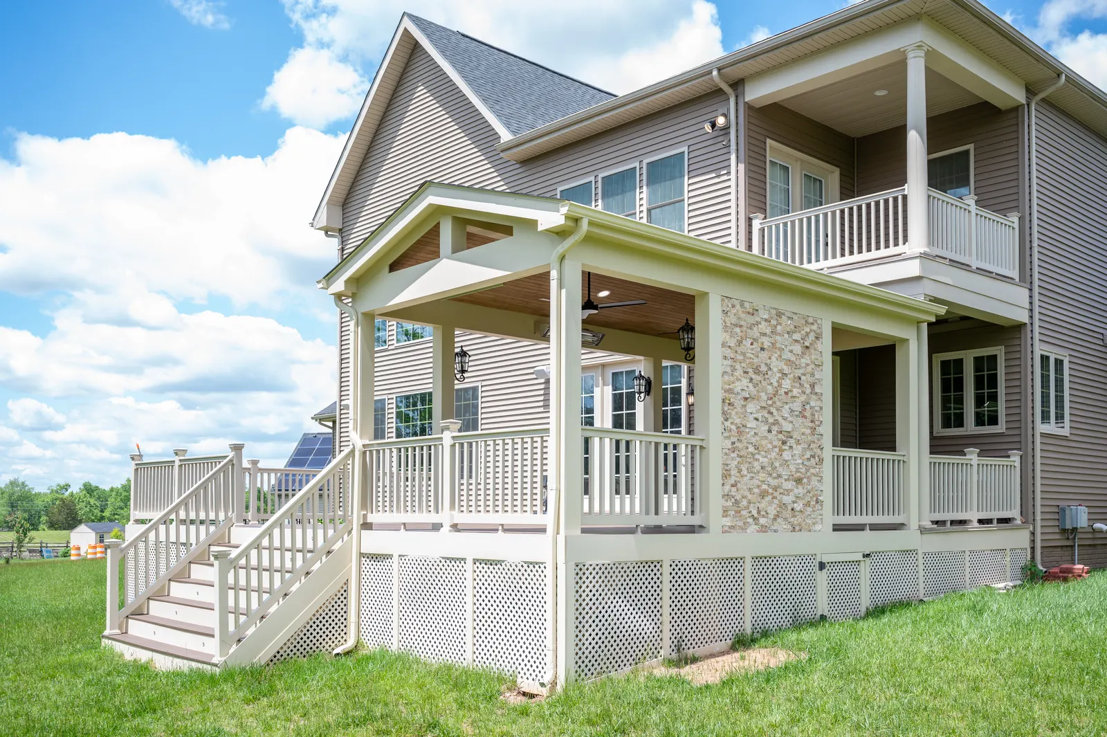 Exterior of the covered deck with stone chimney and white railings
