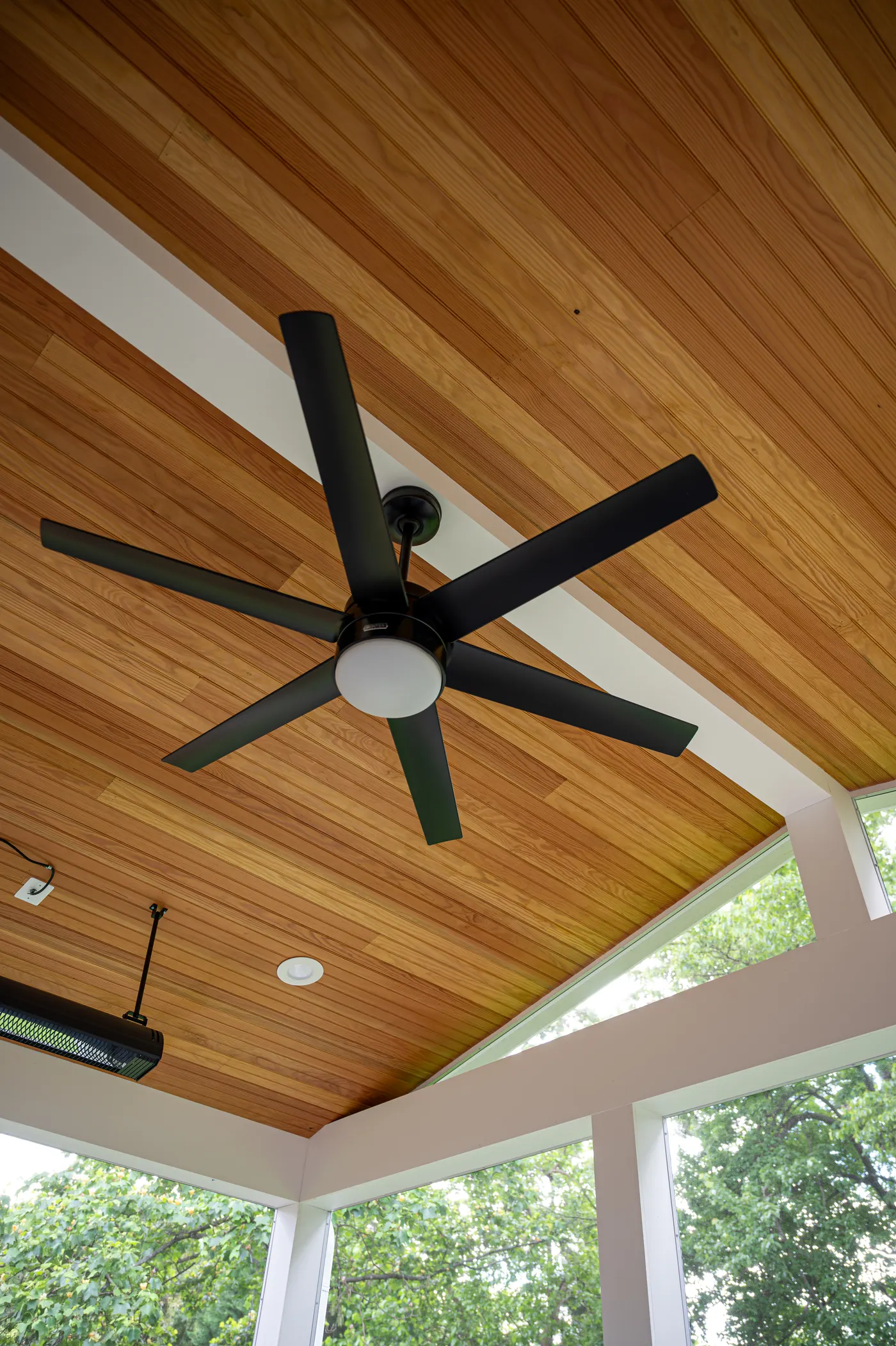 Stained wood plank ceiling with a black ceiling fan