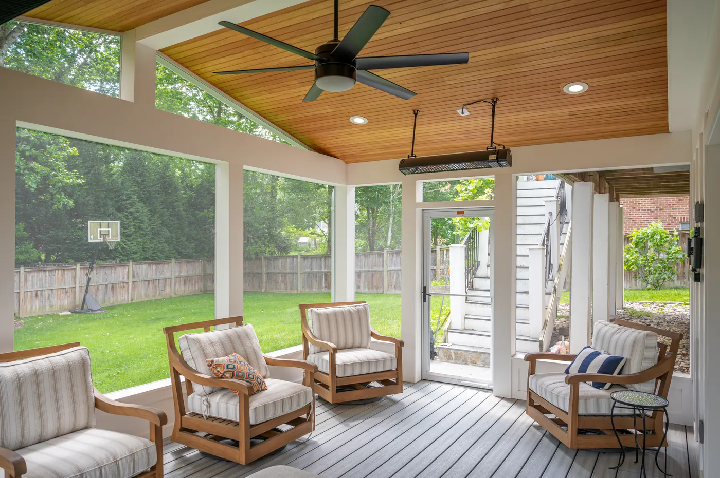 Teak lounge chairs under the wood ceiling, looking out to the yard