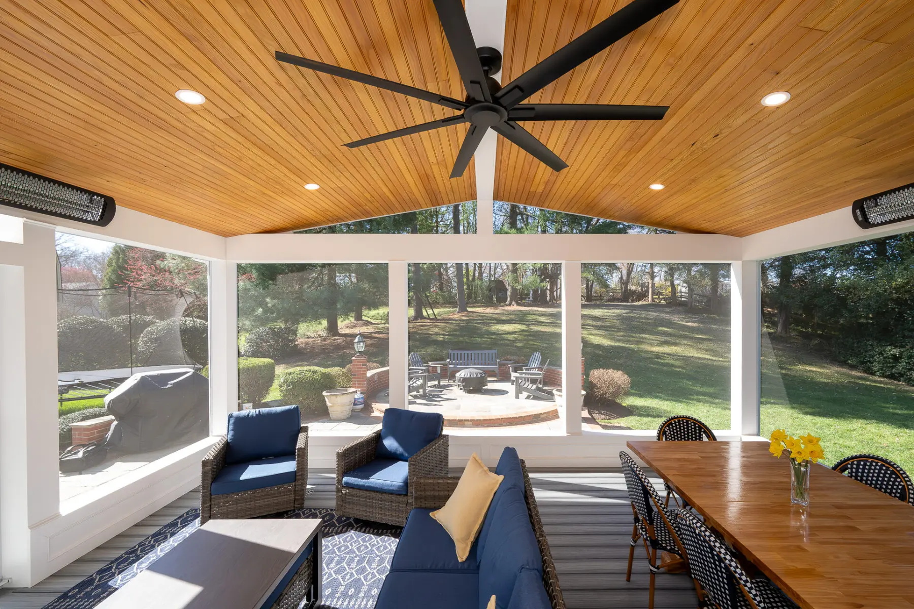 Screened porch seating looking out to a flagstone patio and fire pit