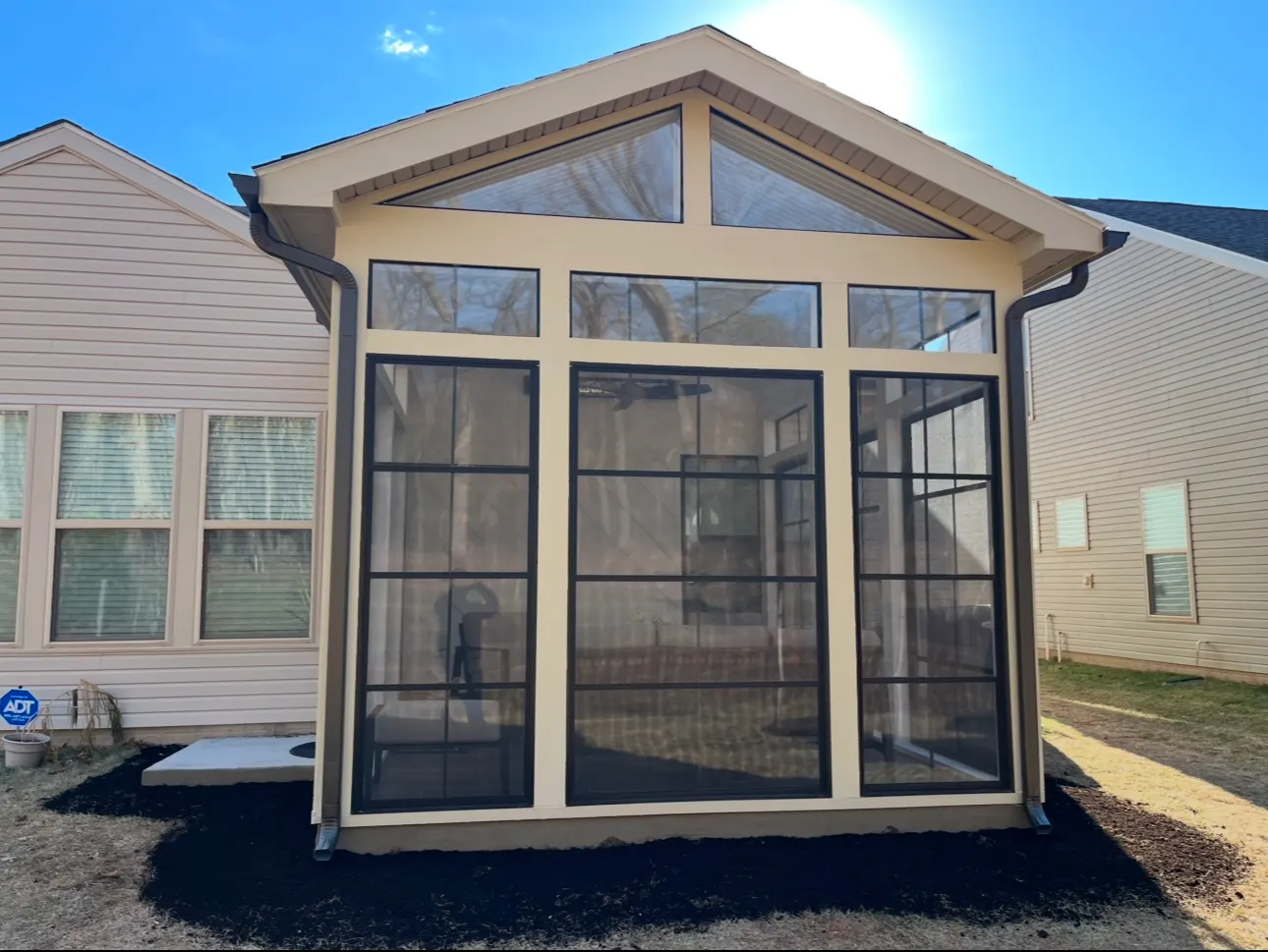Gabled three-season room with tall black-framed windows